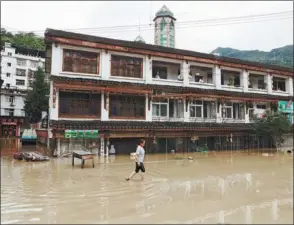  ?? JIANG DONG / CHINA DAILY ?? After days of heavy rain, a resident in Wenxian county, Gansu province wades through the street in rolled up trousers on Tuesday.