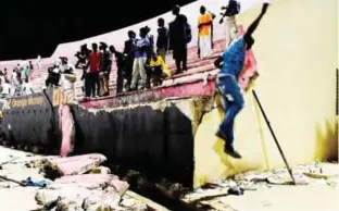  ??  ?? DAKAR: People look at the scene after a wall collapsed at Demba Diop stadium in Dakar after a football game between local teams Ouakam and Stade de Mbour. — AFP