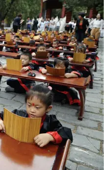  ??  ?? 北京市东城区景泰小学­一年级新生在北京孔庙­大成殿前举行的入学典­礼上诵读古诗