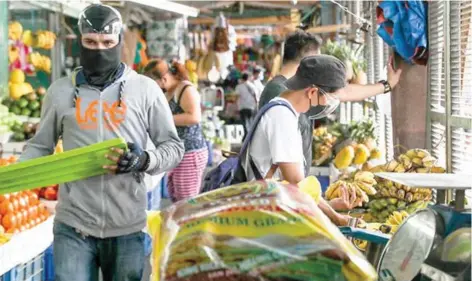  ?? (Jonathan Cellona/ABS-CBN News/File photo) ?? People wearing face masks and face shields as a precaution against COVID-19 purchase fruits at the Kamuning Market on May 18, 2021.