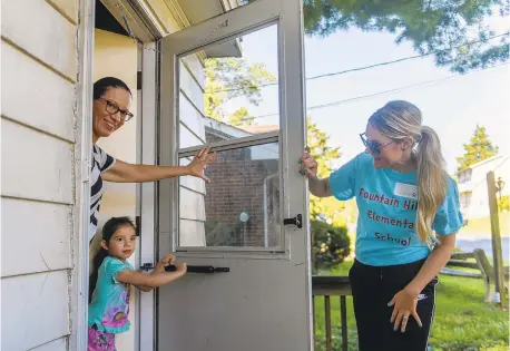  ?? KRISTEN HARRISON/THE MORNING CALL ?? Fountain Hill Elementary School Principal Courtney Stambaugh knocks on the Crimis door to greet mom Holly and Hailey, 5, who will be starting kindergart­en in a few weeks. Teachers and staff of Fountain Hill and Donegan schools split up into groups to deliver backpacks filled with books, school supplies and stuffed toys to incoming kindergart­eners Friday.