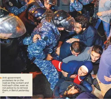  ?? AP ?? Anti-government protesters lie on the road as they scream and hold each other, even as riot police try to remove them, in Beirut yesterday.