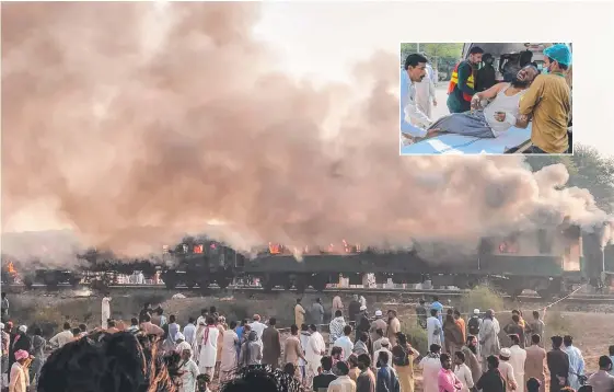  ?? Pictures: AFP/PAKISTAN'S PUNJAB EMERGENCY SERVICE RESCUE ?? Residents gather beside the burnt-out carriages after a passenger train caught fire in the Punjab province in Pakistan; (inset) paramedics shift an injured victim to a hospital in Multan.