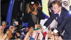  ?? — AFP ?? SEOUL: South Korean presidenti­al candidate Moon Jae-In (right) of the Democratic Party greets his supporters at a park near the presidenti­al Blue House yesterday.