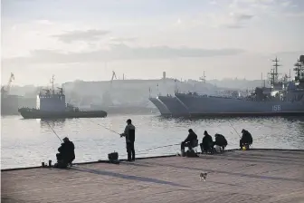  ?? AP ?? Fishermen try to catch fish in front of Russia Navy ships in Sevastopol, Crimea, on Oct. 27, 2014. Ukrainian drone and missile strikes have provided a major morale boost for Kyiv at a time when its undermanne­d and under-gunned forces are facing Russian attacks along the front line.