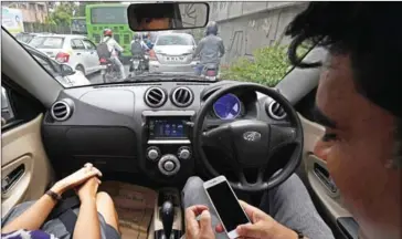  ?? PRAKASH SINGH/AFP ?? Ankur Bhatia (right), head of marketing at Mahindra Electric Mobility, checks his mobile while driving Mahindra’s e2o Plus in New Delhi on July 21.