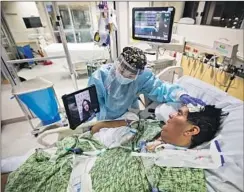  ?? Francine Orr Los Angeles Times ?? NURSE Kat Yi holds an iPad up so Eduardo Rojas’ wife, Angelica, can see him in the ICU at Providence St. Jude Medical Center in Fullerton.