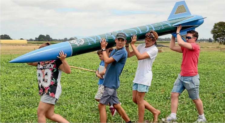  ??  ?? Jack Davies, centre, blue shirt, and helpers carry the record-breaking rocket Marsden.