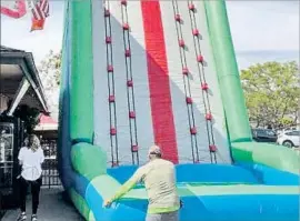  ?? Laycee Barragato Gibson ?? AN INFLATABLE wall is set up Friday at Hennessey’s Tavern in Dana Point. The bar gave a “green card,” a voucher for a free drink, to those who climbed it.