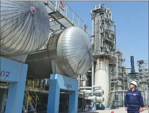  ?? YANG QING / XINHUA ?? A PetroChina technician inspects equipment at an oil refinery in Fushun, Liaoning province. The company’s revenue for the third quarter rose 17 percent from a year ago.