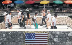  ?? ERIC GAY THE ASSOCIATED PRESS ?? Visitors to the River Walk cross a bride in San Antonio, Texas, on Wednesday. Texas was one of several states that set a single-day record for new virus cases on Tuesday.