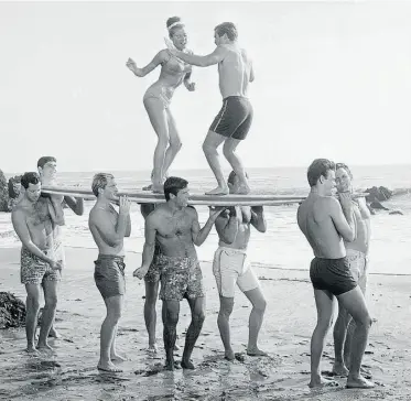  ?? THE ASSOCIATED PRESS ?? Actors amuse themselves while working on a 1965 Hollywood movie at California’s Malibu Beach. Gidget and Moondoggie won’t be catching any waves at Edmonton’s proposed urban beach.