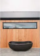 ??  ?? Above: One of the couple’s must-haves was an outdoor bath. The plumbing comes through the home’s exterior wall so it has hot running water. Right: The home has a concrete floor and patio to contrast with the plywood used inside.