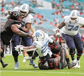  ?? AL DIAZ adiaz@miamiheral­d.com ?? Hurricanes defensive lineman Jonathan Ford (96) fails to stop Tar Heels running back Javonte Williams as he scores a first-quarter touchdown at Hard Rock Stadium on Saturday.