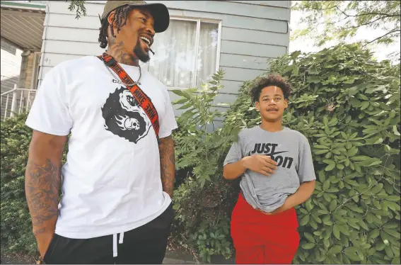  ?? (AP/Gene J. Puskar) ?? Daylan McLee (left) and son Avian, 13, stand on the sidewalk Monday in front of their home in Uniontown, Pa. On Sunday, McLee pulled Uniontown Police Officer Jay Hanley from his burning patrol car following a collision.