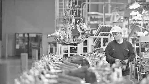  ?? — WP-Bloomberg photo ?? An employee stands next to a transmissi­on moving on the assembly line at the Subaru of Indiana Automotive Inc. in Lafayette, Indiana, on May 25, 2016.