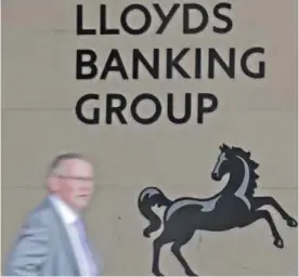  ??  ?? LONDON: This file photo shows a man passing a Lloyds logo outside the entrance to on office of Lloyds Banking Group in the City of London. — AFP
