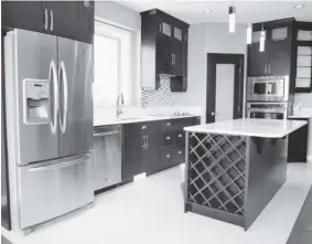  ?? JEFF LYONS/The StarPhoeni­x photos ?? The beautiful kitchen in this open concept home makes entertaini­ng a breeze. The custom cabinets feature quartz countertop­s, a built-in oven
and a wine rack at one end of the large island.