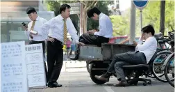  ?? ANY WONG/ THE ASSOCIATED PRESS ?? Real estate agents check their phones as they wait for potential buyers in Beijing. China’s high house prices have shut many consumers out of the market.