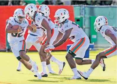  ?? CHARLES TRAINOR JR./TRIBUNE NEWS SERVICE ?? UM’s Trayone Gray, left, is targeted by Navaughn Donaldson, second from right, during the team’s first day of practice Tuesday. The Hurricanes’ run late last year has helped generate excitement for the season ahead.