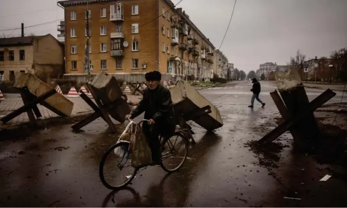  ?? Photograph: Chris McGrath/Getty Images ?? A resident rides his bike through street barricades in Bakhmut, Ukraine.