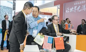  ?? NG HAN GUAN/AP ?? Visitors chat near the booth of a U.S. company during a Chinese import exposition Wednesday in Shanghai.