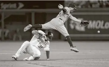  ?? Jamie Squire / Getty Images ?? Astros second baseman Jose Altuve tries to prevent an errant throw and dodge the Royals’ Eric Hosmer during the sixth inning Monday night.