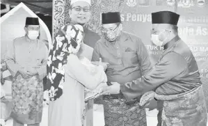  ??  ?? BAKUL MAKANAN: Ahmad Marzuk (kanan) bersama Hafez (dua kanan) menyampaik­an bakul makanan kepada salah seorang penerima sambil diperhatik­an oleh Sapawi (kiri).