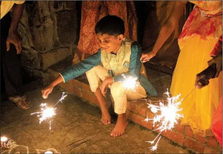  ?? Arkansas Democrat-Gazette/FRANCISCA JONES ?? Karthik Thotakura holds out one of the sparklers lighting the night at a Diwali gathering in Little Rock on Tuesday.