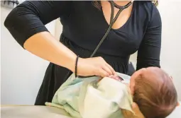  ?? AMR ALFIKY/AP ?? A pediatrici­an examines a newborn baby in her clinic in 2019 in Chicago. The American Academy of Pediatrics says it intends to eliminate “race-based” medicine.