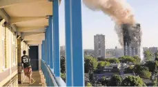  ?? MATT DUNHAM/AP ?? A resident in a nearby building watches smoke rise from London’s Grenfell Tower in 2017. Faulty building materials helped spread a devastatin­g fire there, according to a lawsuit.