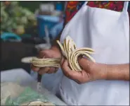  ?? ?? Otzoy counts her handmade corn tortillas at her market stall.