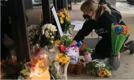  ?? Photograph: Elijah Nouvelage/Getty Images ?? A woman adjusts flowers and signs outside Youngs Asian Massage where four people were shot and killed on 17 March in Acworth, Georgia.