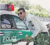  ??  ?? A child is evacuated from Iran’s parliament building, right, during the siege. Left, an officer shelters behind a police car during the attack