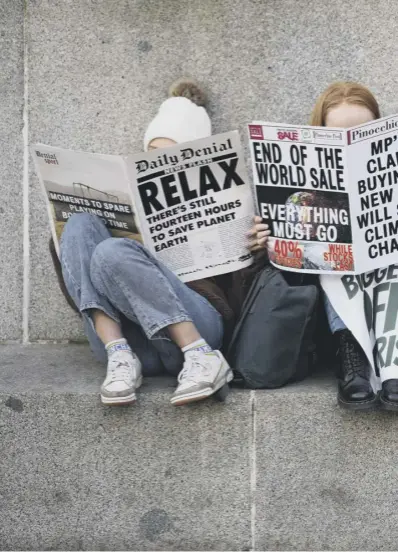  ?? ?? 0 Climate change activists read mock newspapers in George Square, Glasgow, in support of victims