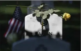  ?? WASHINGTON POST PHOTO BY MATT MCCLAIN ?? A flower sits on a headstone as people visit in observance of Memorial Day at Arlington National Cemetery.