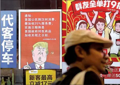  ?? AP ?? A poster outside a restaurant in China’s Guangdong province depicts President Donald Trump and warns that American customers will be charged 25% more than others.