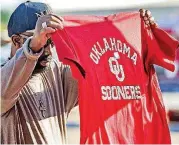  ?? THE OKLAHOMAN] [PHOTO BY CHRIS LANDSBERGE­R, ?? University of Oklahoma fan Stanley Rogers looks at a T-shirt at Bevo Bash in Marietta.