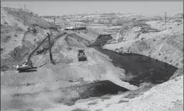  ?? IRFAN KHAN/ LOS ANGELES TIMES ?? A crew works on seepage of 900,000 gallons of oil and brine from an abandoned well in Chevron Corp’s Cymric Oil Field that has transforme­d a dry creek bed into a black lagoon in McKittrick, California.