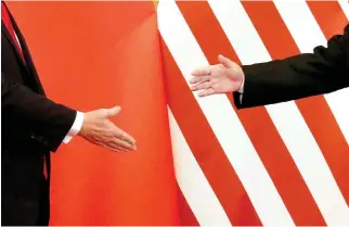  ??  ?? A NOV. 9, 2017 file photo shows China’s President Xi Jinping and US President Donald Trump reaching out to shake hands after making joint statements at the Great Hall of the People in Beijing, China.