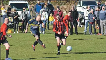  ?? 01_B12footbal­l07 ?? Ryan Armstrong chases after the ball while an appreciati­ve Arran audience looks on.