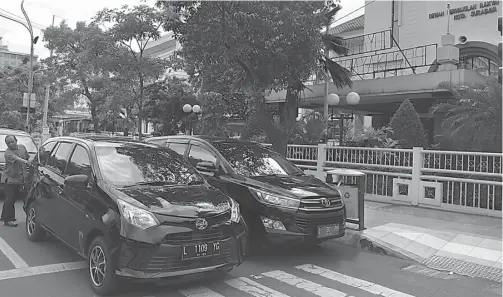  ?? DITE SURENDRA/JAWA POS ?? CONTOH BURUK: Belasan mobil pejabat pemkot dan anggota DPRD Surabaya terparkir di depan gedung DPRD kemarin. Padahal, saat ini mereka membahas raperda soal parkir.