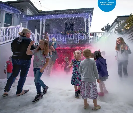  ?? Picture / Dean Purcell ?? Kids play in the snow and fog during the turning on of the Franklin Rd Christmas lights in Ponsonby. Watch the video at nzherald. co. nz