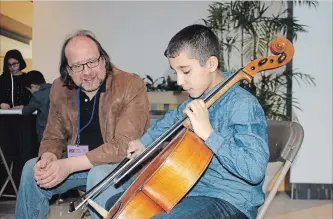  ?? ALLAN BENNER THE ST. CATHARINES STANDARD ?? Walid Bakhit, who has lived in Canada for the past year after escaping the war in Syria, gets some tips from Niagara Symphony Orchestra cellist Gordon Cleland at an instrument petting zoo, at the Pen Centre, Saturday.