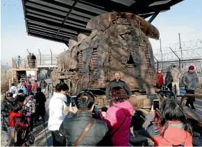  ?? AP ?? Tourists view a rusty steam train that was damaged during the Korean War, at the Imjingak Pavilion in Paju, near the DMZ in South Korea.