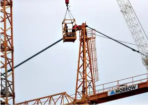  ?? Associated Press ?? ■ Workers in a bucket hoisted by a crane begin the process of preparing the two unstable cranes for implosion at the collapse site of the Hard Rock Hotel, which underwent a partial, major collapse while under constructi­on Oct. 12 in New Orleans. Plans have been pushed back a day to bring down two giant, unstable constructi­on cranes in a series of controlled explosions before they topple onto historic New Orleans buildings, the city's fire chief said Friday, noting the risky work involved in placing explosive on the towers.