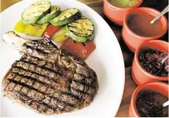  ?? Melissa Phillip / Houston Chronicle ?? A cowboy bone-in rib-eye with grilled vegetables is served along with four salsas at Saltillo Mexican Kitchen.