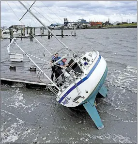  ?? AP/TOM COPELAND ?? Police officer Curtis Resor (left) and Sgt. Micheal Stepehens check a sailboat Friday in Beaufort, N.C., after Hurricane Dorian passed the North Carolina coast and caused flooding in some low-lying areas.