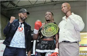  ?? Picture: MARK CARRELS ?? HERO CHAMP: Makana’s Bongani Fule proudly shows off his Eastern Cape Junior Lightweigh­t belt after winning the vacant title against Mvuzo Kotobe at the TT Jonas Sports Centre. Celebratin­g with him are Boxing SA director of operations Mandla Ntlanganis­o, left, and promoter Bongani Zulu.