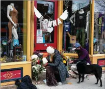  ?? ELIZA EARLE/NEW YORK TIMES ?? Alinka Zellner and Miles Mcdonald bring flowers and hang a sign that reads “Lonna” outside Umba, a shop in Boulder, Colorado, that sells yoga and festival clothing, and was managed by Tralona Lynn “Lonna” Bartkowiak, one of the shooting victims.